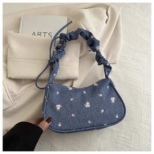 Gros plan d'un sac cabas en denim bleu à fleurs avec poignée plissée de style vintage