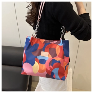 Detail of colorful geometric print tote bag featuring a leather logo and chain strap