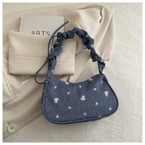Détail du sac hobo en jean floral avec bandoulière à volants et décoration de nœud