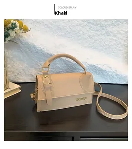 Detail view of khaki crossbody bag with top handle and gold lettering on premium leather
