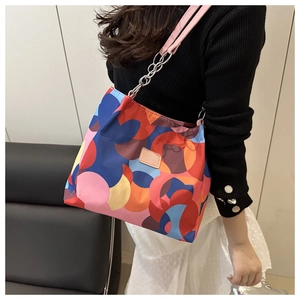 Large floral nylon tote bag with colorful abstract pattern and chain strap on model