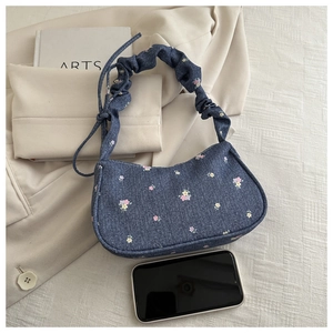Détail du sac en denim fleuri avec bandoulière froncée et référence de taille au téléphone