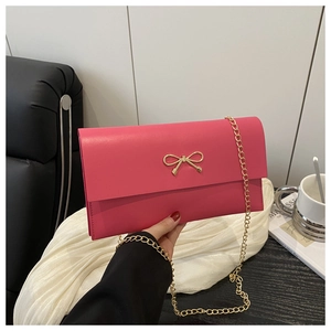 Detail of rose pink envelope chain bag with a gold bow buckle on a minimal background