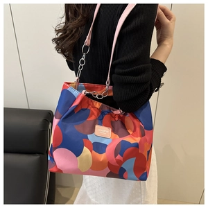 Detail of colorful oxford fabric tote bag with chain strap worn by a female model