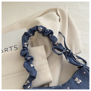 Détail du sac bandoulière en denim avec motifs ours et bandoulière froncée sur blazer