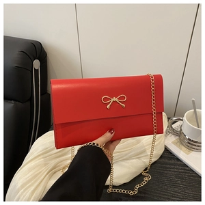 Close-up of red envelope chain bag featuring a delicate gold bow metal buckle detail