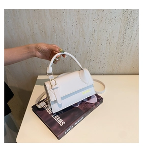 Close-up of white minimalist crossbody bag with gold lettering and adjustable strap