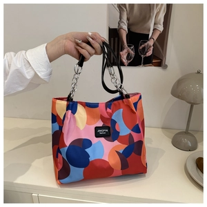 Detail showing colorful geometric waterproof nylon tote bag and silver chain handle