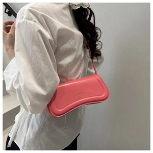 Detail of a bright pink leather crescent shoulder bag with golden logo on white shirt