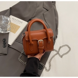 Détail du mini sac carré en cuir caramel avec boucle argentée et bandoulière chaîne