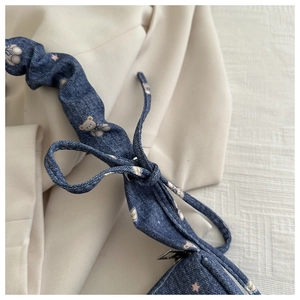 Détail de la bandoulière en denim avec imprimé ours et décoration de nœud papillon