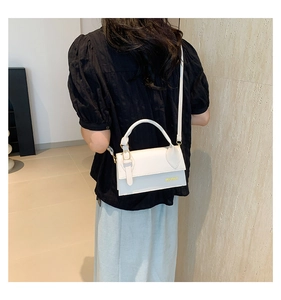Rear view of a model wearing a white rectangular leather handbag with a gold logo