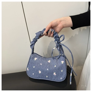 Détail du sac bandoulière en denim avec imprimé floral et nœud papillon sur la anse