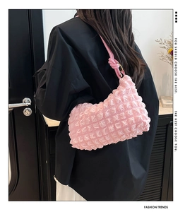 Close-up of pink bubble textured pleated underarm bag worn over the shoulder