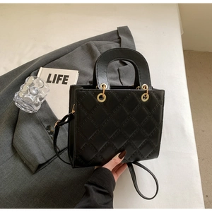Close-up of black quilted leather texture and gold hardware on a luxury handbag