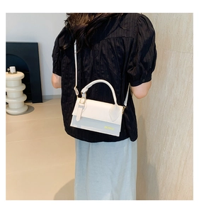 Detail of white mini leather crossbody bag with gold logo and circular top handle