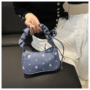 Détail du sac hobo en jean avec motif floral rose et décoration de nœud sur le côté