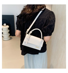 Detailed side view of a white rectangular crossbody bag on a model's shoulder