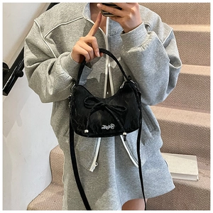 Detail of black hobo bag featuring a decorative bow and white scripted brand logo