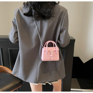 Vue arrière du mannequin portant un mini sac bandoulière rose avec chaîne argentée et poignée