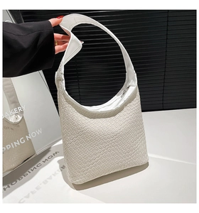 Detailed close-up of the white woven leather hobo bag texture and sleek metallic zipper