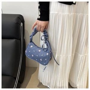 Détail du sac à main en denim bleu fleuri avec poignée froncée et nœud latéral