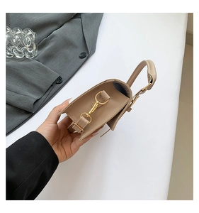 Detail view of khaki leather square handbag with golden hardware and top handle