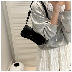 Detailed side view of a black leather underarm bag styled with a casual outfit