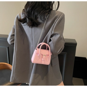 Mini sac bandoulière rose avec chaîne argentée porté par un mannequin en veste chic