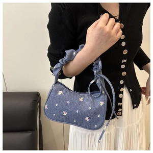 Sac bandoulière en denim fleuri avec anse plissée et nœud porté par un mannequin