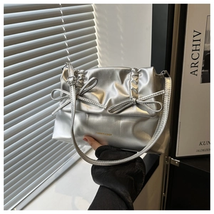 Details der metallisch silbernen Umhängetasche mit Faltenoptik und Zierschleifen