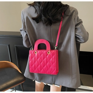 Detail view of fuchsia quilted handbag with gold hardware and top handle shown on model