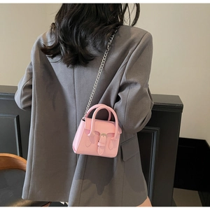 Mini sac carré rose avec chaîne argentée porté par un mannequin, vue détaillée du style