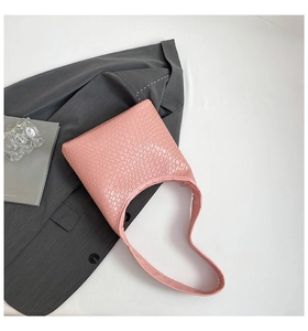 Detail of pink crocodile embossed shoulder bag styled with blazer and magazines