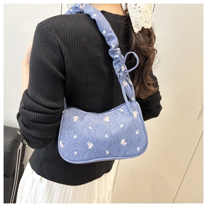 Détail du sac floral en denim bleu avec bandoulière plissée et nœud décoratif