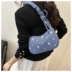 Gros plan du sac en jean fleuri avec bandoulière plissée et détails noués