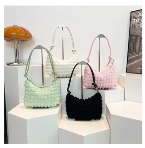 Detail showing bubble texture pleated crescent bags in green, cream, pink, and black