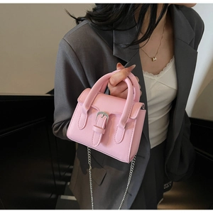 Close-up of pink mini crossbody bag with silver buckle and thin metal chain strap detail