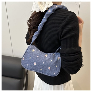 Détail du sac sous le bras en denim fleuri avec bandoulière froncée et forme croissant