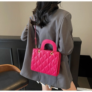 Dettaglio della borsa trapuntata magenta con manici rotondi e tracolla indossata dal modello