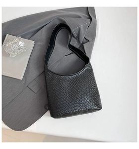 Detailed view of black woven texture shoulder bag on a grey blazer for daily workwear