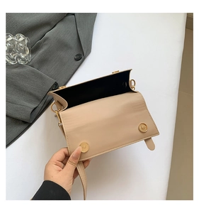 Detail view of the open beige crossbody bag with golden hardware and black lining interior