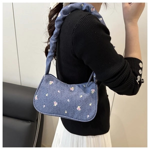 Détail du sac bandoulière en jean fleuri avec bandoulière à volants sur un mannequin