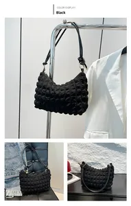 Three-way view of a black bubble-textured underarm bag on a hanger and chair