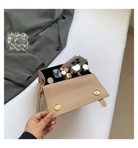 Detail view of beige square bag interior showing storage for phone and lipstick