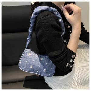 Gros plan d'un sac hobo en denim bleu avec motifs floraux et une bandoulière à volants style nuage