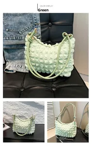 Detail of light green bubble texture fabric and thin double straps on a pleated shoulder bag