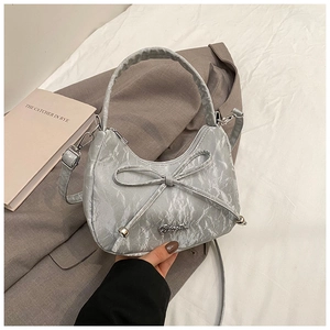 Detail of silver pleated crescent bag with bow decoration and metallic brand logo