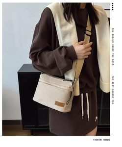 Close-up of a beige nylon crossbody bag with brown wide adjustable strap on a model