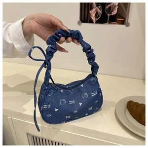 Détail du sac à épaule en denim bleu avec nœud décoratif et poignée à volants chic
